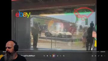 Glass waterfall installation in front of an eBay display with people and a sports car behind it
